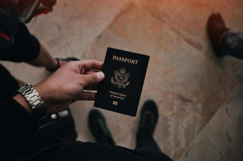 Diverse man with silver wristwatch holds passport over marble floor. International business.