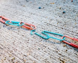 Blue and red paper clips, broken chain on concrete, representing divorce, multi-state US divorce