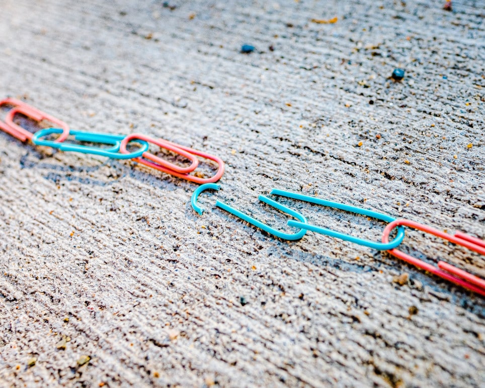 Blue and red paper clips, broken chain on concrete, representing divorce, multi-state US divorce