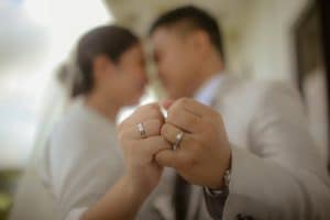 Newlyweds out of focus join hands with close up of wedding rings