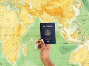 Hand holding passport held up against world map