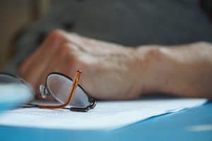 Hand with spectacles resting on documents