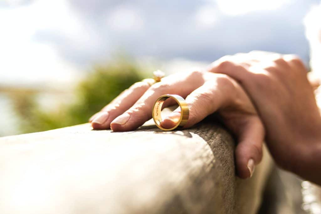 Folded hands, foreshortened perspective resting on fence, removing wedding ring, divorce, contemplative, divorce mediation