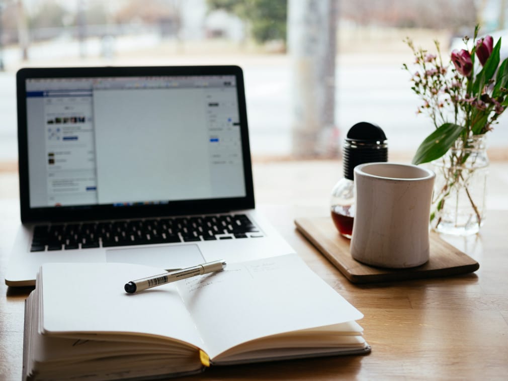 Computer in home with coffee mug, planner and flower vase, divorce planning