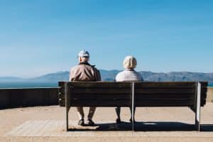 Older couple sitting on a bench staring at mountain few, slightly apart, divorce over 50