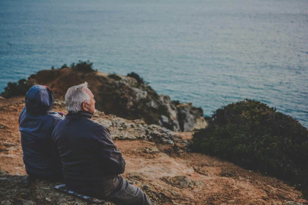 older couple sitting in picturesque seaside environment watching the sunset, grey divorce longterm marriage