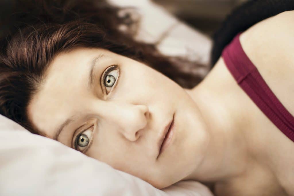 Close up of woman in bed with thoughtful look