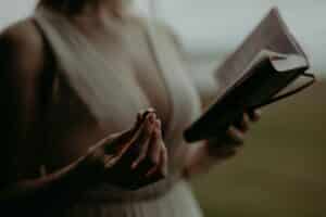 Woman holding wedding ring while looking at diary